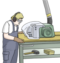 Eine Person trägt Arbeits-Kleidung. Sie steht vor einem Arbeits-Tisch. Dort steht eine große Säge-Maschine drauf. Die Person sägt damit eine Holzplatte.